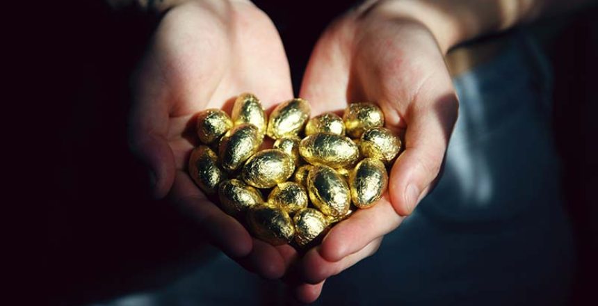 hands holding a pile of gold eggs